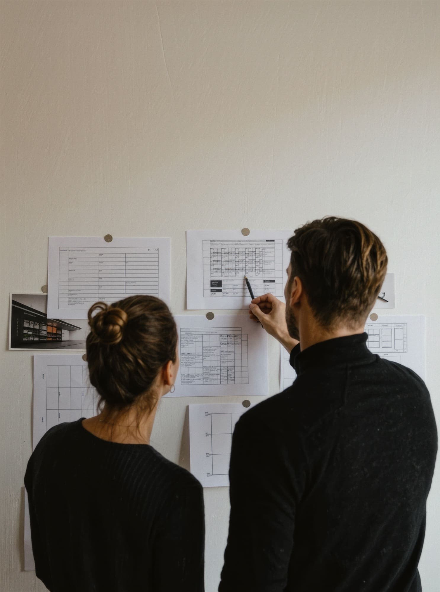 Two designers reviewing wireframes pinned to a studio wall